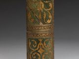 an old wooden cylinder with a green and gold design on it