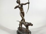 une image représentant une statue en bronze d'une femme tenant un arc et accompagnée d'un chien