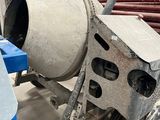 une bétonnière posée dans un garage, avec des outils par terre