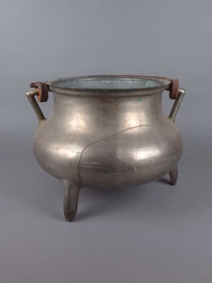 une vieille théière en argent posée sur un socle en bois