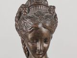 an antique bronze statue of a woman with a flower in her hair