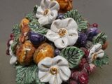 une figurine en céramique représentant des fleurs et des fruits posés sur une table
