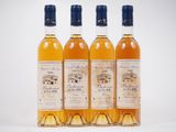 quatre bouteilles de vin sont alignées sur une surface blanche