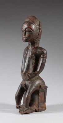 une figurine en bois représentant un homme assis sur un tabouret