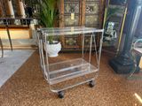 a clear glass trolley with a plant on top of it