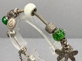un gros plan d'un bracelet posé sur un support transparent, orné d'une perle verte