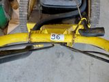 a yellow lawn mower sitting on the floor in a garage