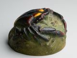 sculpture of a crab sitting on a rock on a white surface