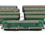 three green train cars sitting next to each other on a white surface