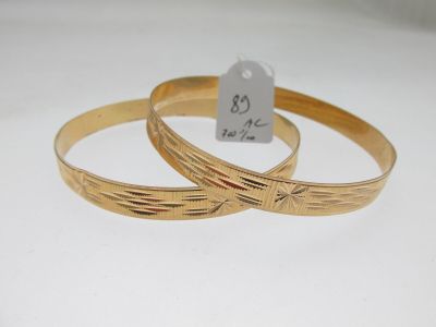 deux bracelets en or posés sur une surface blanche, accompagnés d'une étiquette de prix