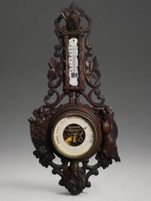 a wooden clock with a barometer on top of it