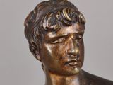 bronze statue of a young man with his head turned to the side