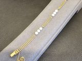 chaîne en or avec des perles et une clé, sur un écrin gris