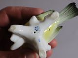 a hand holding a small figurine of a bird