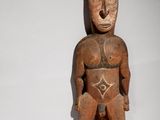 an image of a wooden statue of a man sitting on a white surface