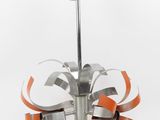a metal sculpture with orange and silver ribbons on it