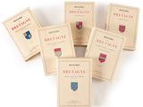 six livres posés sur une surface blanche, surmontés d'un blason rouge et bleu