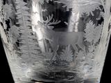 a glass vase with a deer and trees etched on it