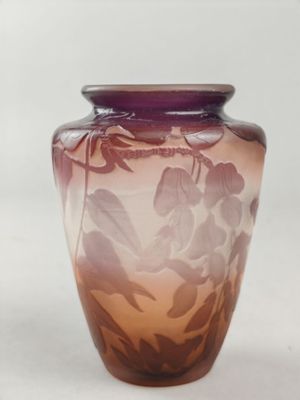 a purple vase with leaves on it on a white surface