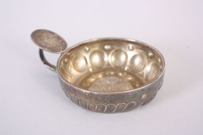 a silver bowl with a spoon in it on a white surface