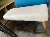 a small white bench with a blue chair behind it