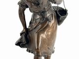 bronze statue of a woman with a basket on her shoulder