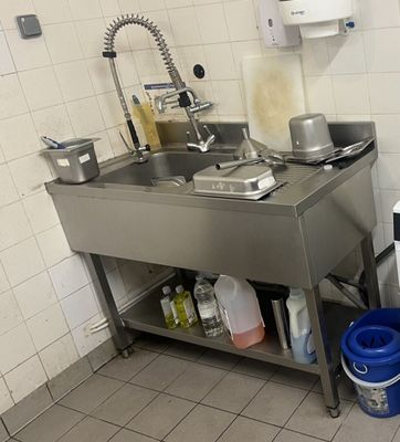 une cuisine équipée d'un évier, d'une cuisinière et d'une poubelle