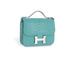 a small turquoise bag with a metal handle on a white background