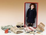une poupée posée dans une boîte à côté de quelques vêtements