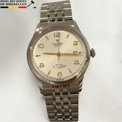 a silver watch with a white dial on it