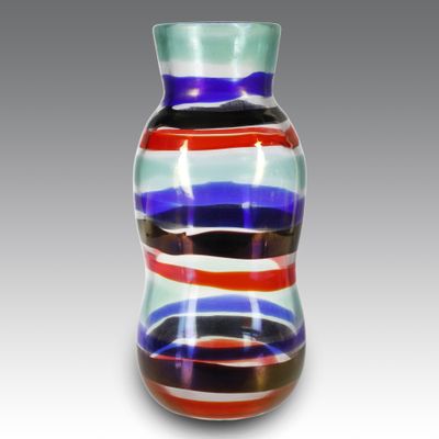 un vase en verre multicolore posé sur une surface blanche