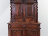 une vieille armoire en bois au plateau sculpté, dans une pièce