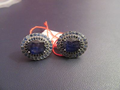 paire de boucles d'oreilles en tanzanite et saphir bleu sur un fond noir