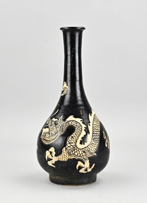 un vase noir et doré orné d'un motif représentant un dragon