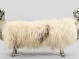 a sheep that is sitting on a bench made of metal