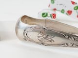 a silver bracelet with a spoon on it next to a pair of scissors