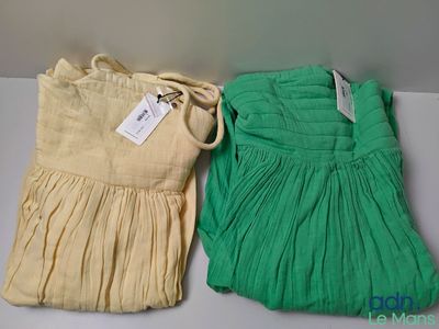 pair of green and yellow dresses with tags on them sitting on a table