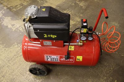 a red air compressor sitting on the floor in the garage