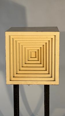 a small square shaped object on a stand with a shadow