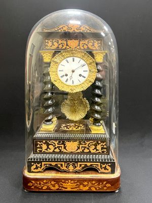 une horloge posée sur une table, sous un dôme en verre