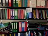books and binders are stacked on a shelf in a room