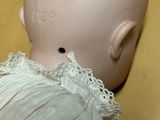 a doll with a white dress on it ' s head next to a vase