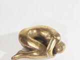 brass figurine of a sleeping cat on a white surface