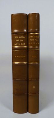 two brown books sitting on top of each other on a white surface