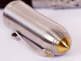 a silver and gold lighter sitting on a white surface