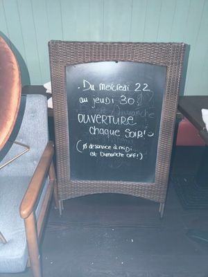 une ardoise posée sur une chaise, devant une autre chaise