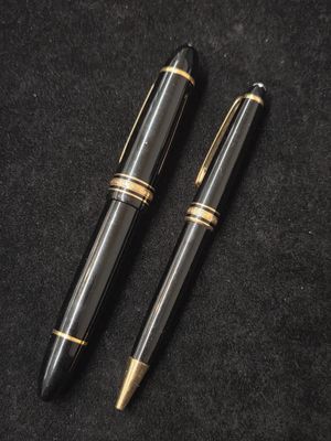deux stylos noirs et dorés posés l'un à côté de l'autre sur une surface noire