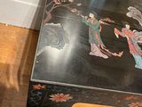 a black table with a painting on it and a vase on the table