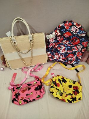 three purses and a handbag sitting on a bed