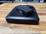 une photo montrant un petit appareil noir posé sur une table en bois